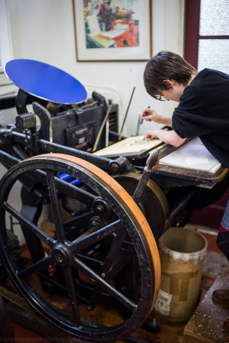 Tess LeNoir works the press at Beacon Hill-based Day Moon, the printing company started by her parents, Jack and Maura, in the 1970s.